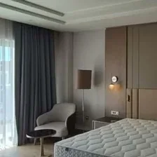 Açık tonlu duvar panelleri ve yatak başlığıyla otel odası