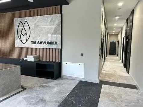 Ahşap lambri duvar ve mermer TM Savunma logo paneliyle resepsiyon ve koridor