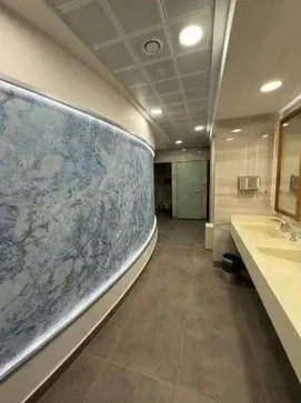 Işıklı kavisli duvar ve lavabo tezgâhı bulunan ıslak hacim