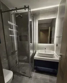 Cam duş kabinli, gri kaplamalı banyo